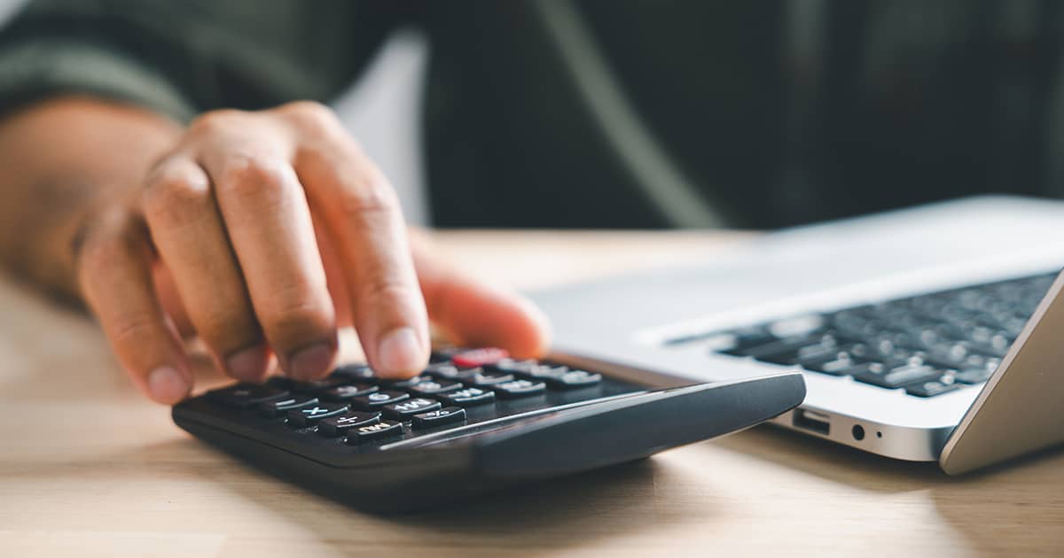 Hand entering budget information on calculator
